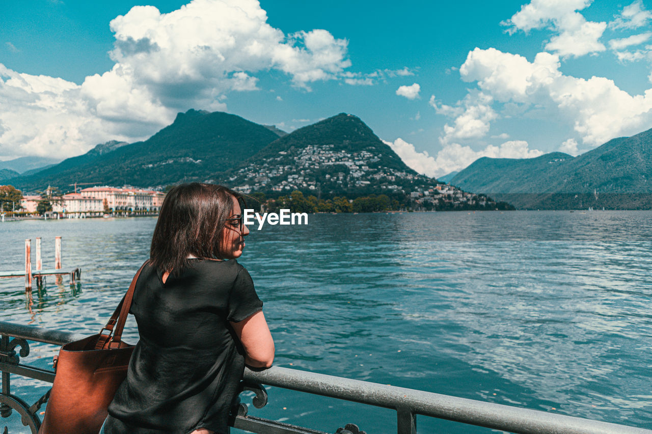 Rear view of woman looking at lake against mountains