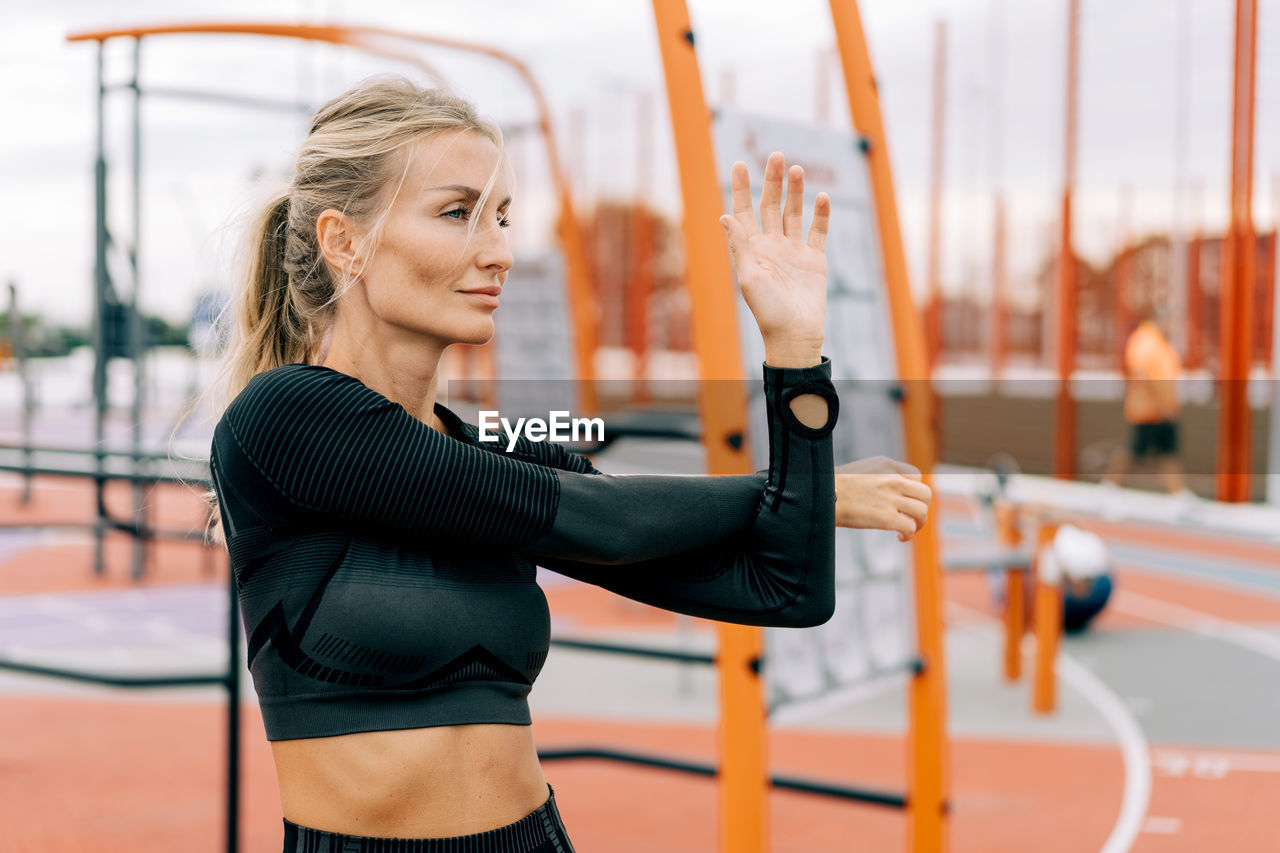 Strong athletic woman stretches her muscles after strength training.