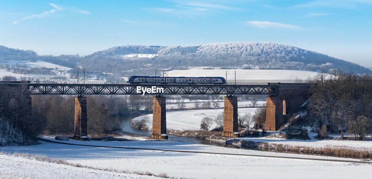 Road by river against sky during winter