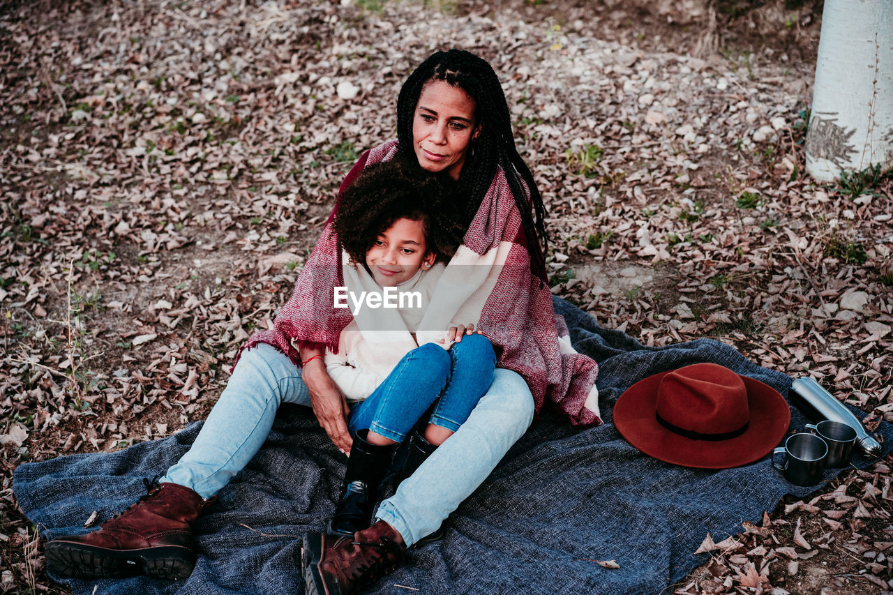 Smiling daughter sitting with mother on land