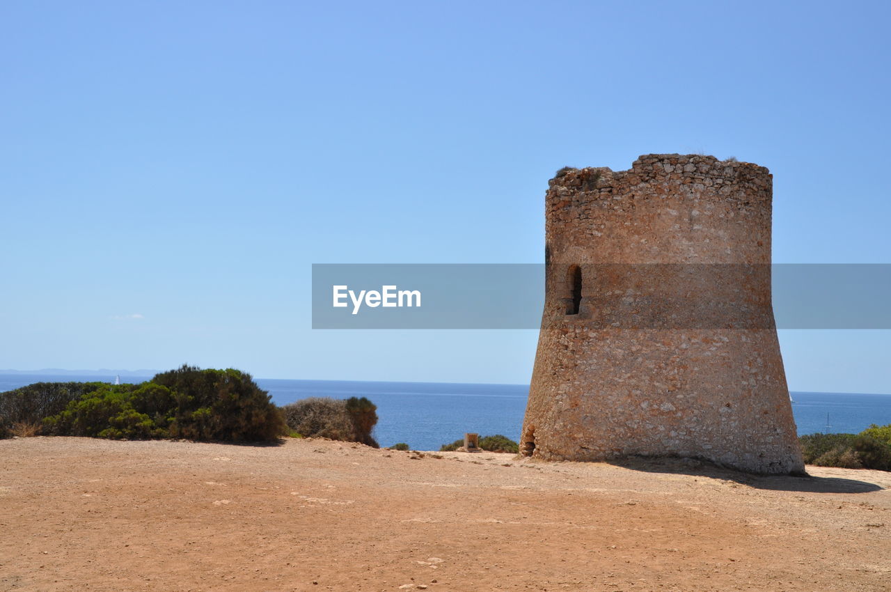 View of ruins at sea against clear blue sky