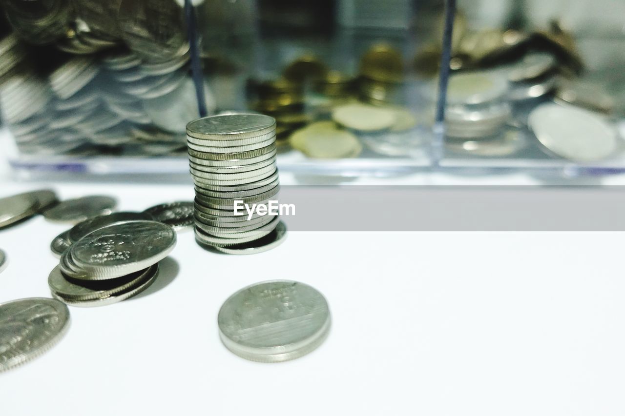 HIGH ANGLE VIEW OF COINS ON TABLE AGAINST WHITE BACKGROUND