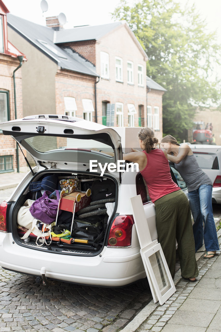 Women loading luggage on car roof