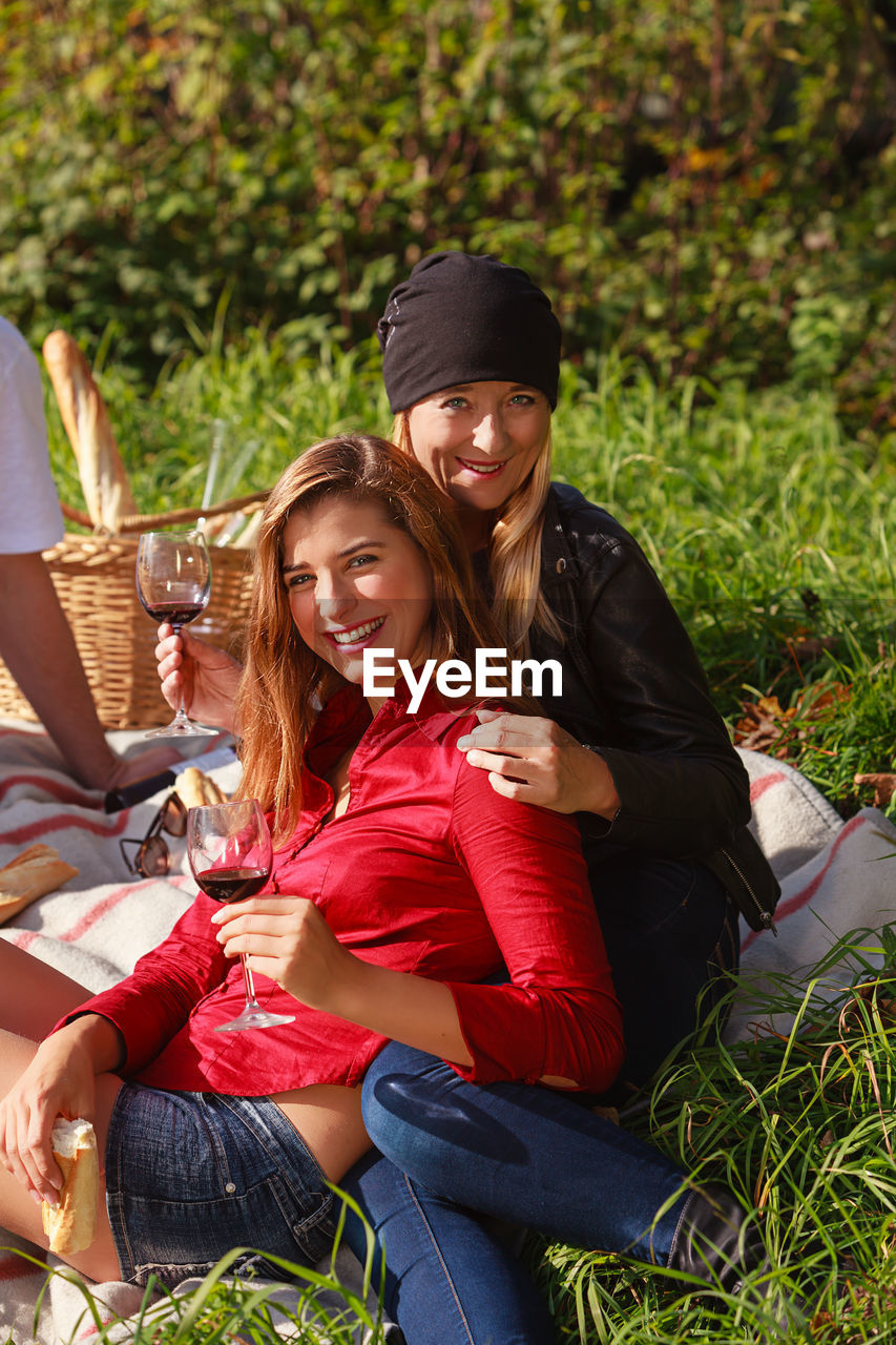 Portrait of smiling female friends sitting on grassy land in park