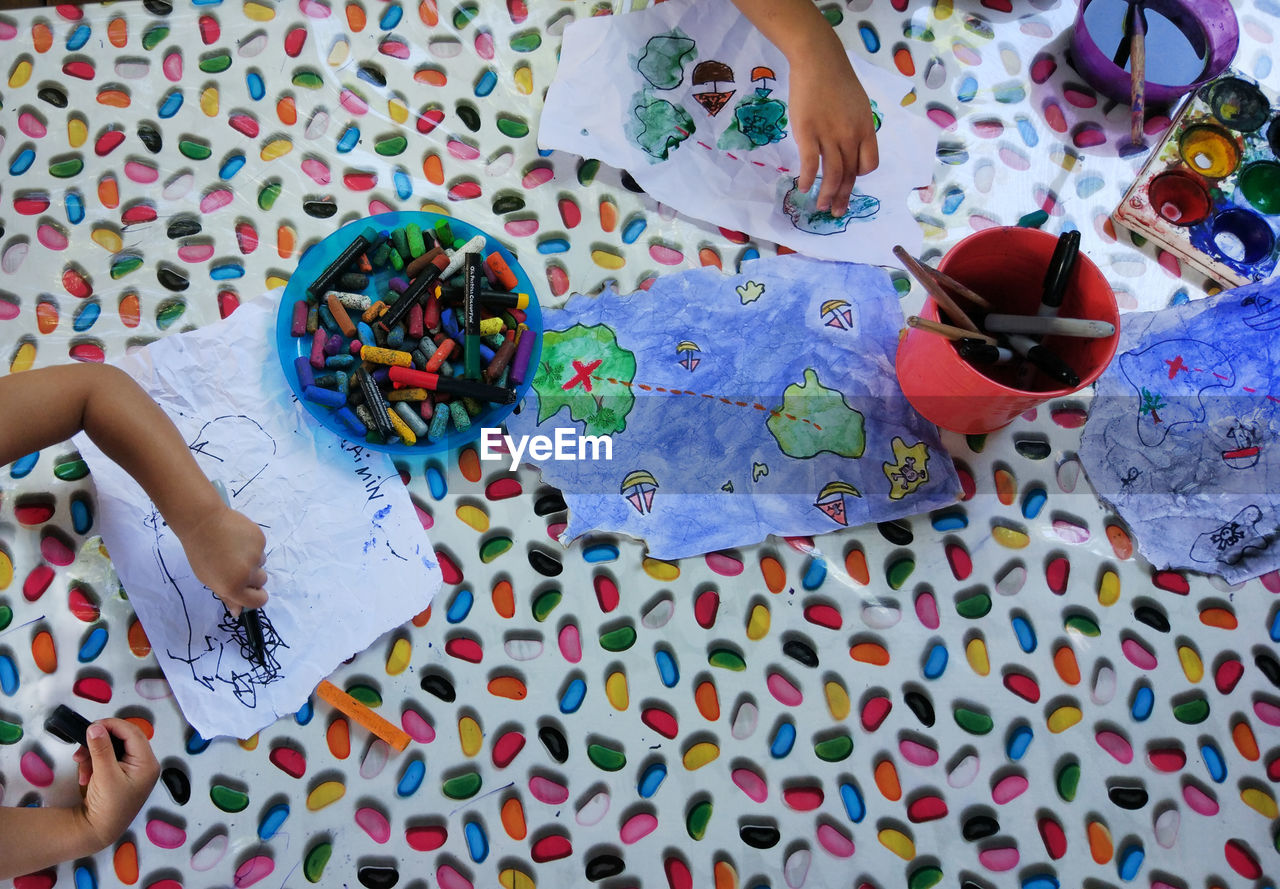 Cropped hands of children drawing on papers