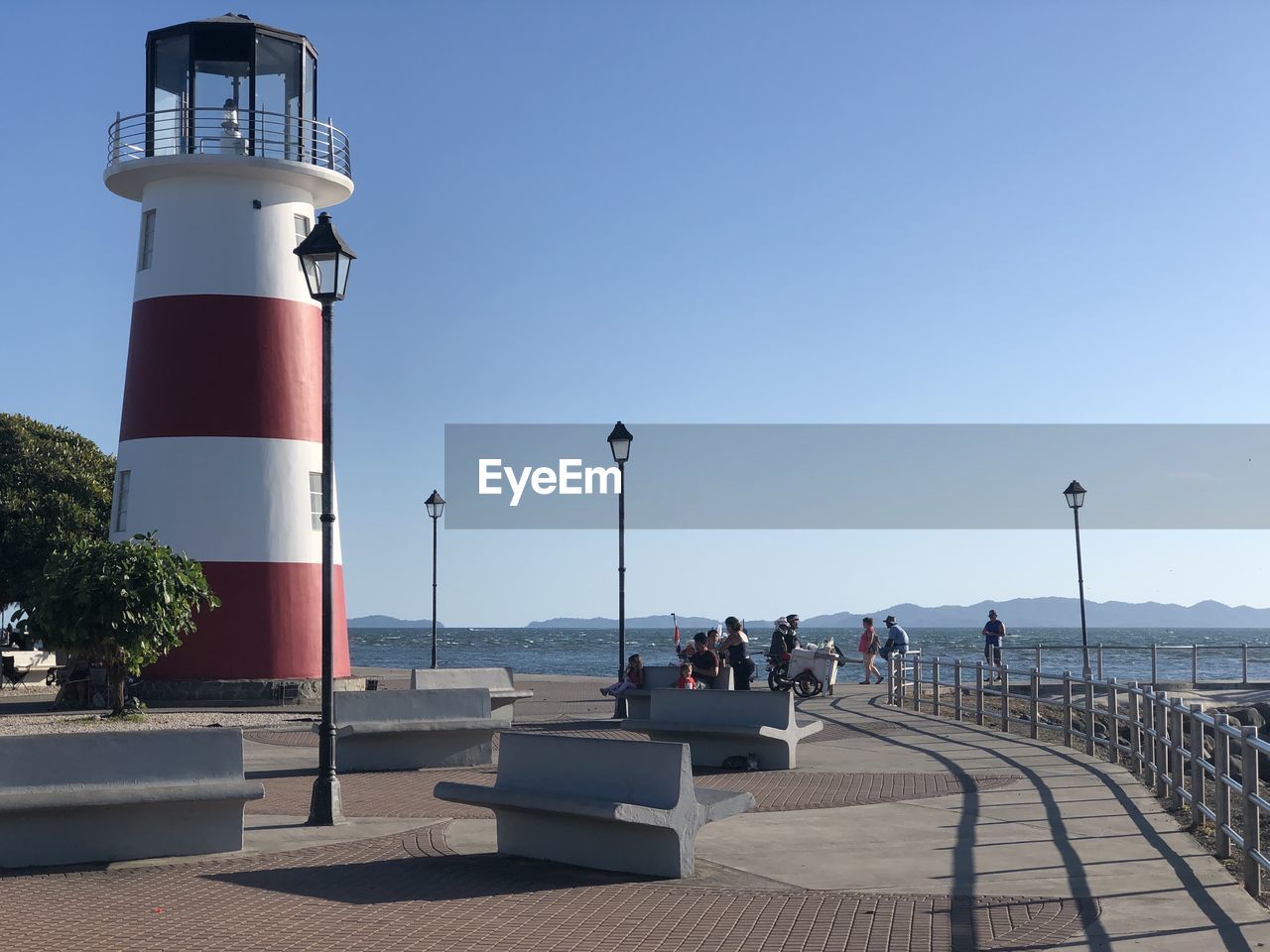 Lighthouse by sea against clear sky