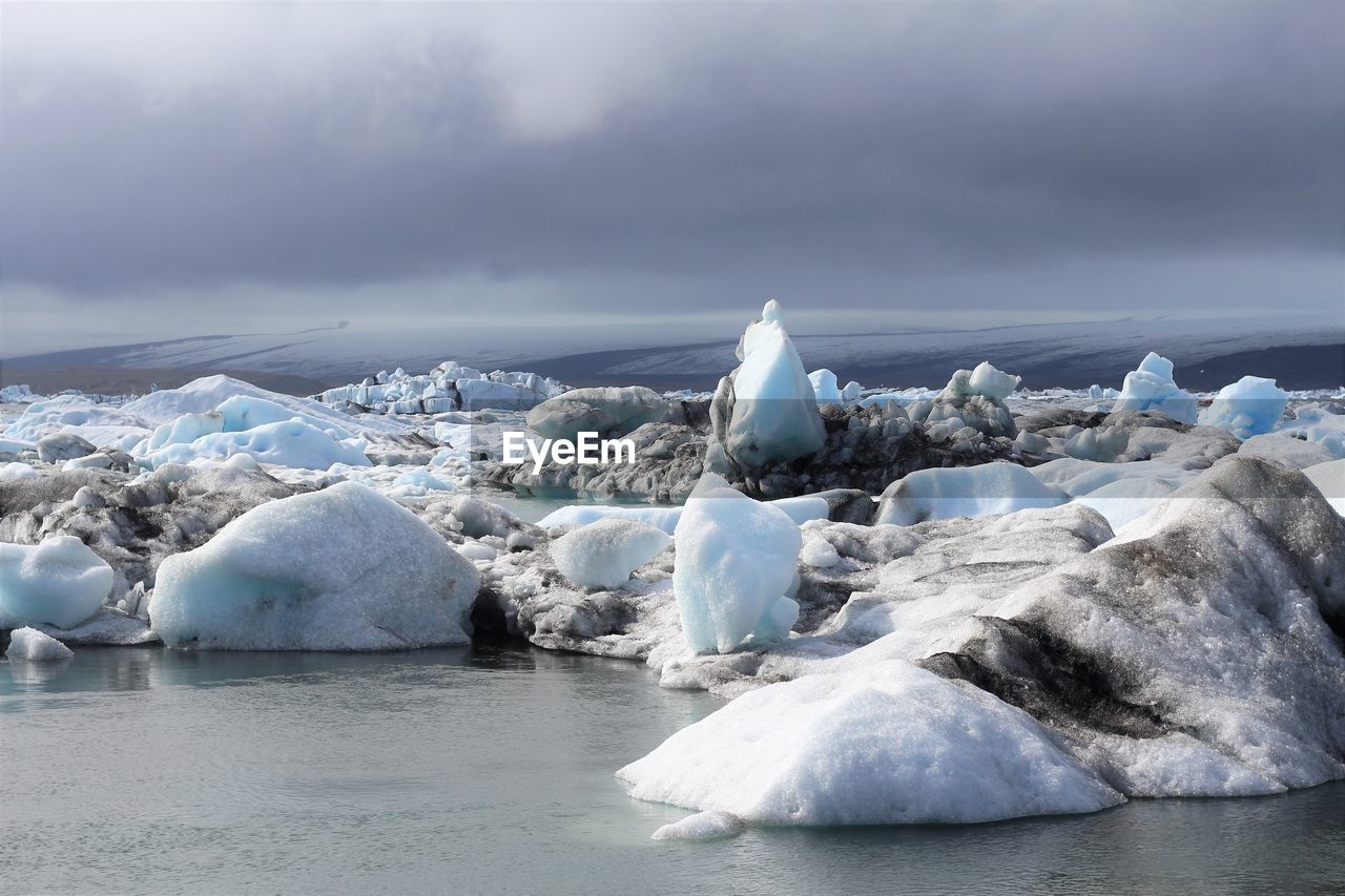 Snow covered landscape by sea against sky