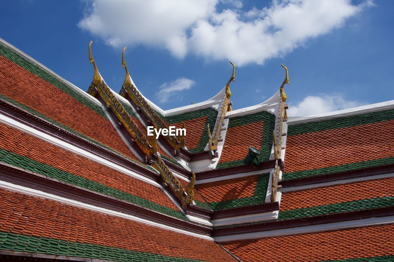 Low angle view of ornate thai temple rooftop against sky
