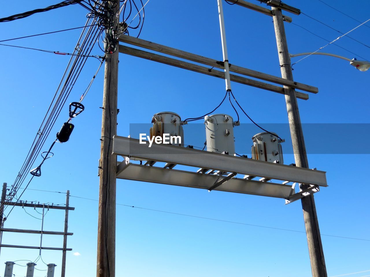 Low angle view of electricity pylon against blue sky