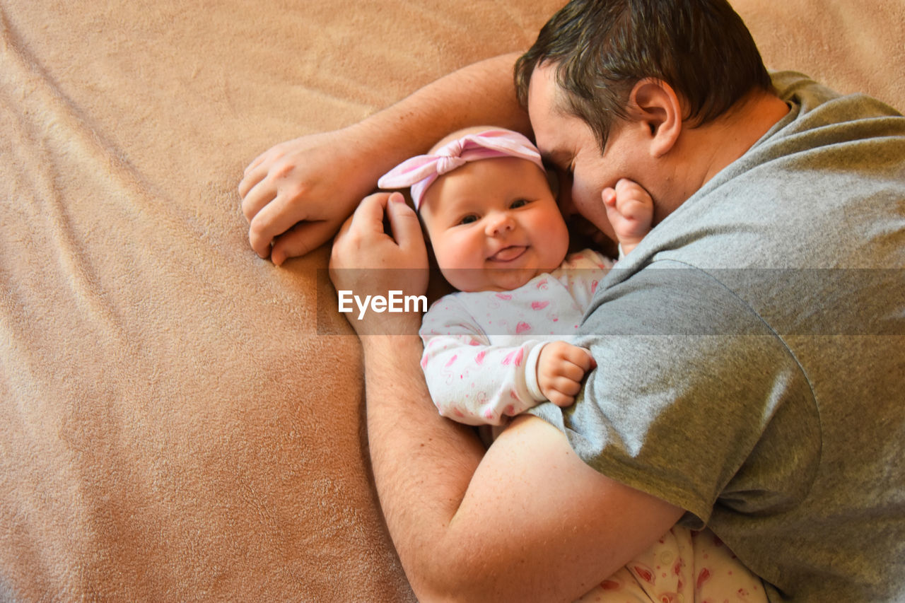 High angle view of smiling baby with father on bed