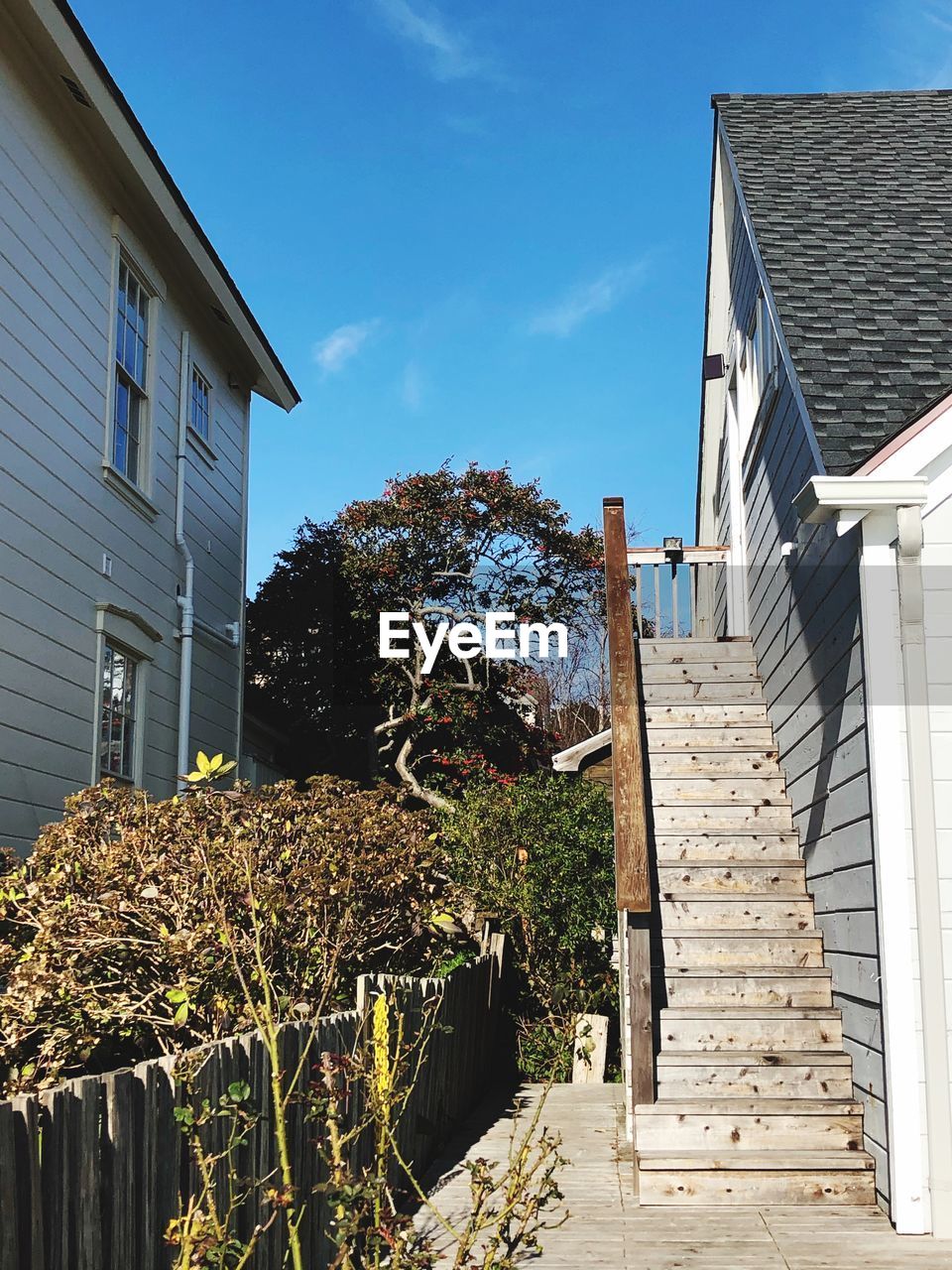 LOW ANGLE VIEW OF BUILDING BY HOUSE AGAINST SKY