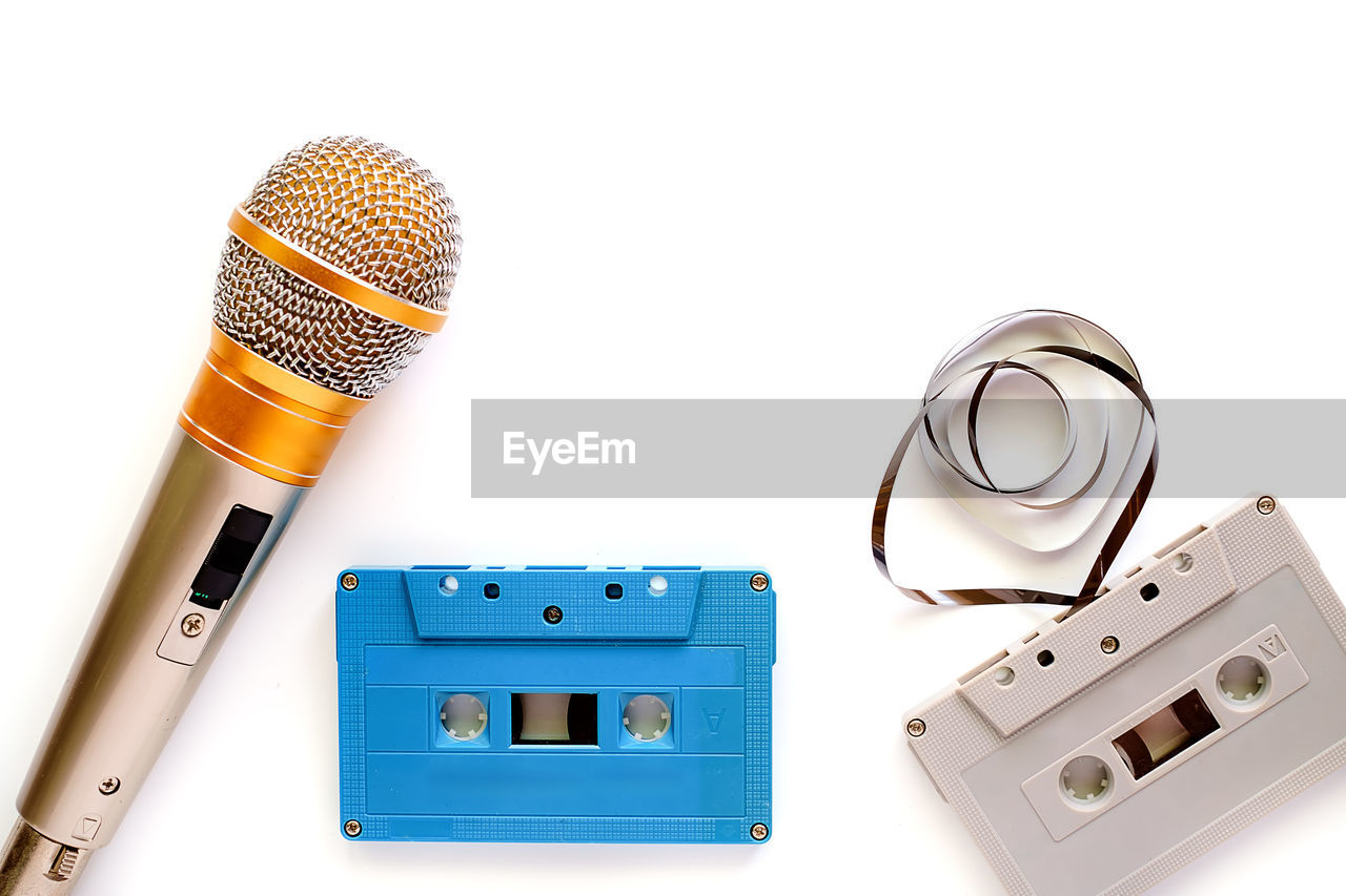 High angle view of microphone by cassette tapes against white background