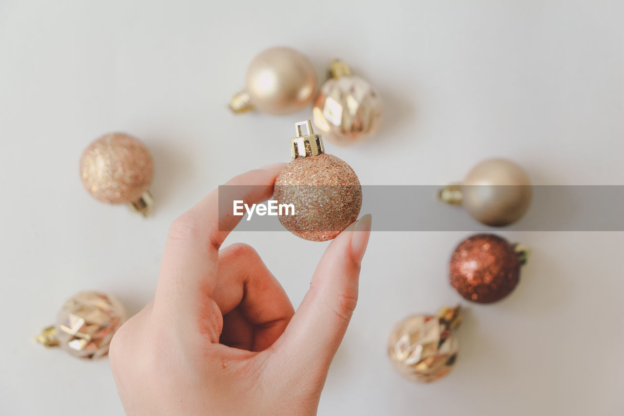 Cropped image of woman hand holding christmas ornament in hand against white background