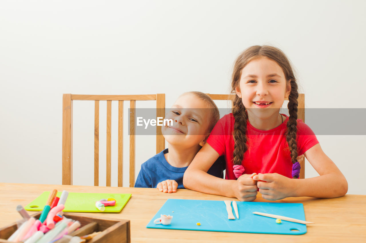 PORTRAIT OF A SMILING GIRL SITTING AT TABLE