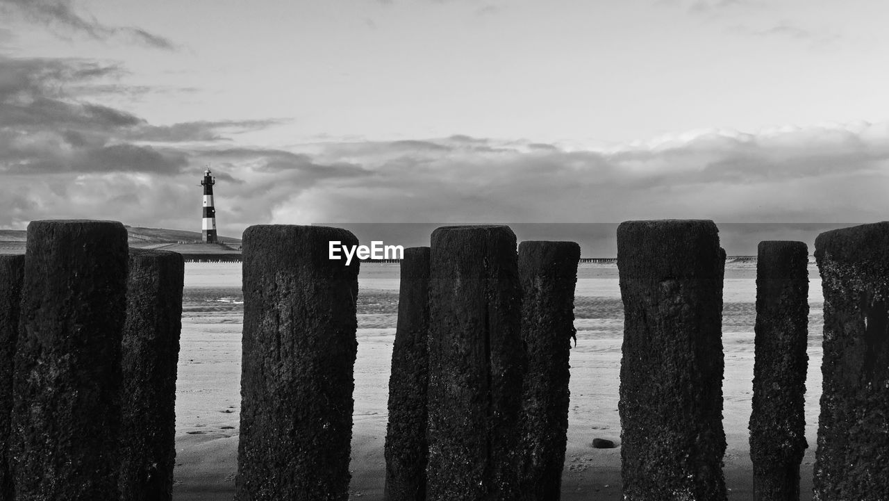 VIEW OF WOODEN POSTS ON SEA AGAINST SKY