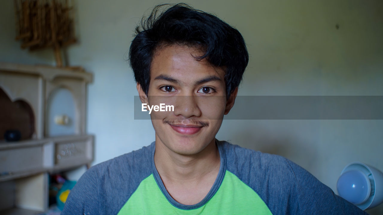 PORTRAIT OF SMILING YOUNG MAN WEARING EYEGLASSES