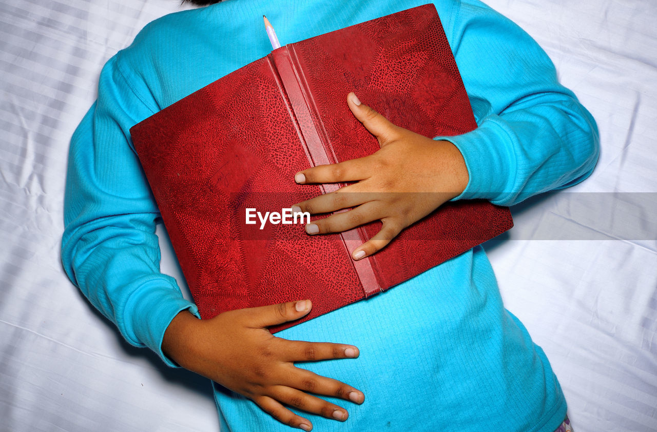 Midsection of person with book on bed