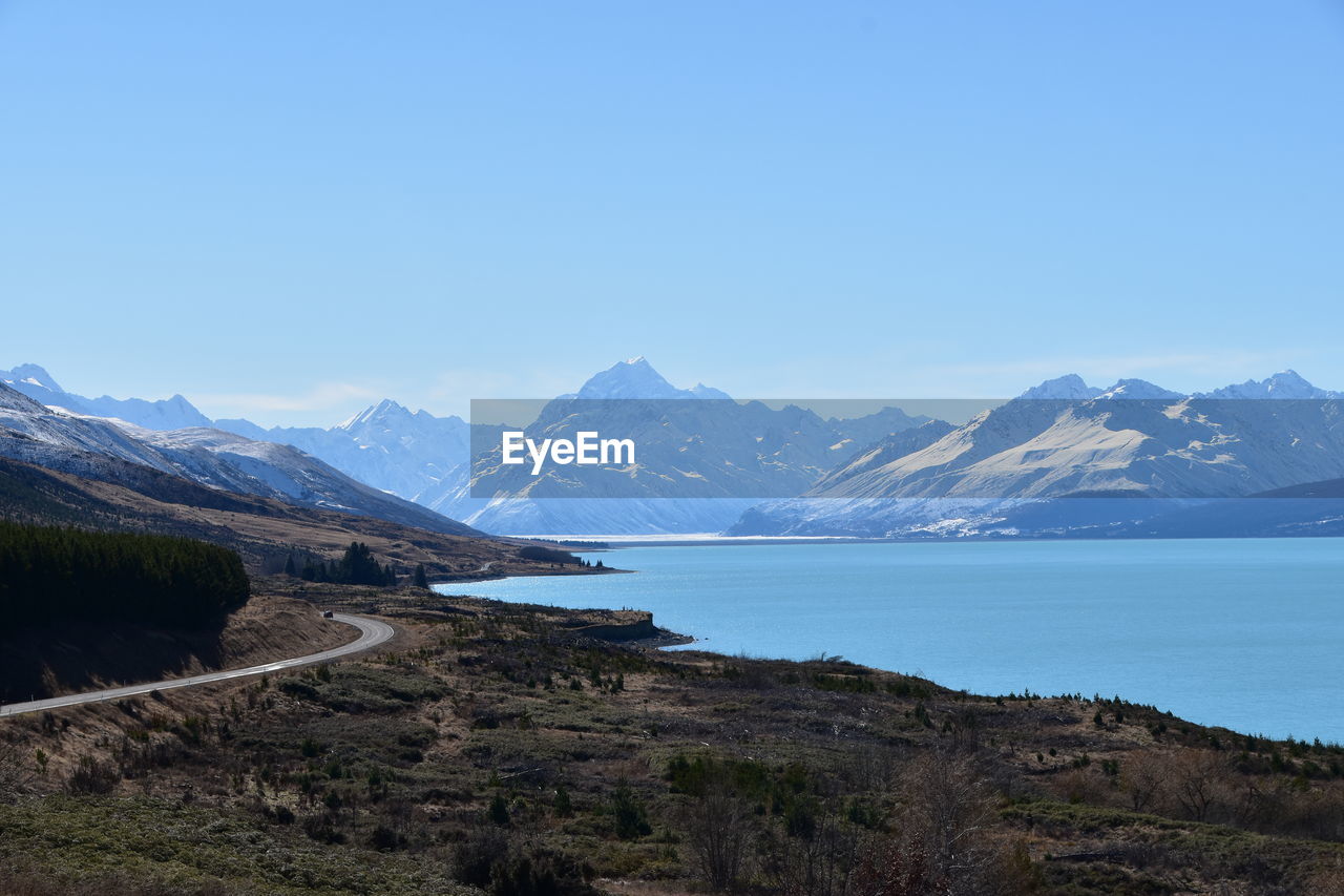 Scenic view of lake and mountains against clear blue sky