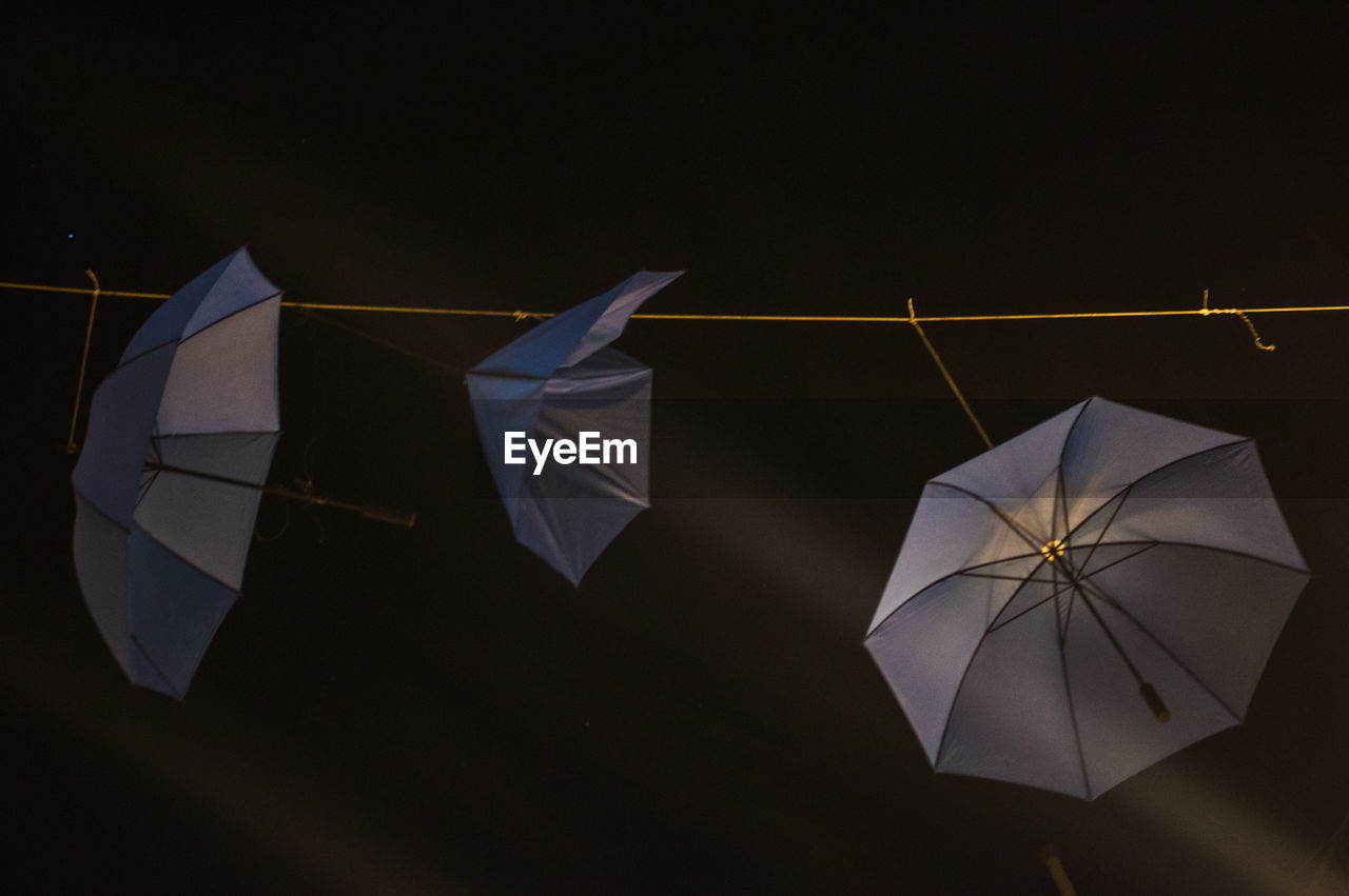 Low angle view of umbrellas hanging against sky at night