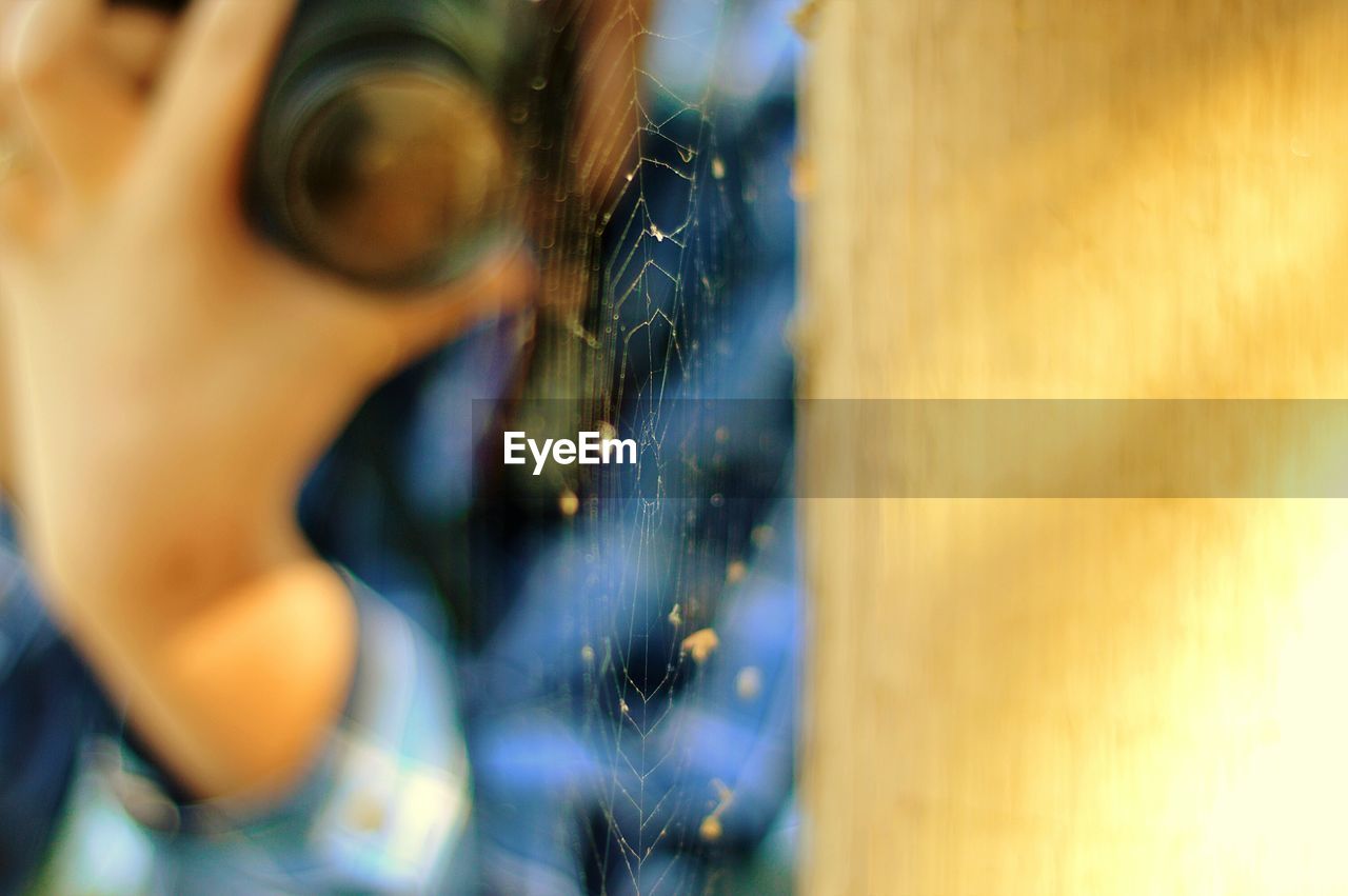 Midsection of person photographing spider web