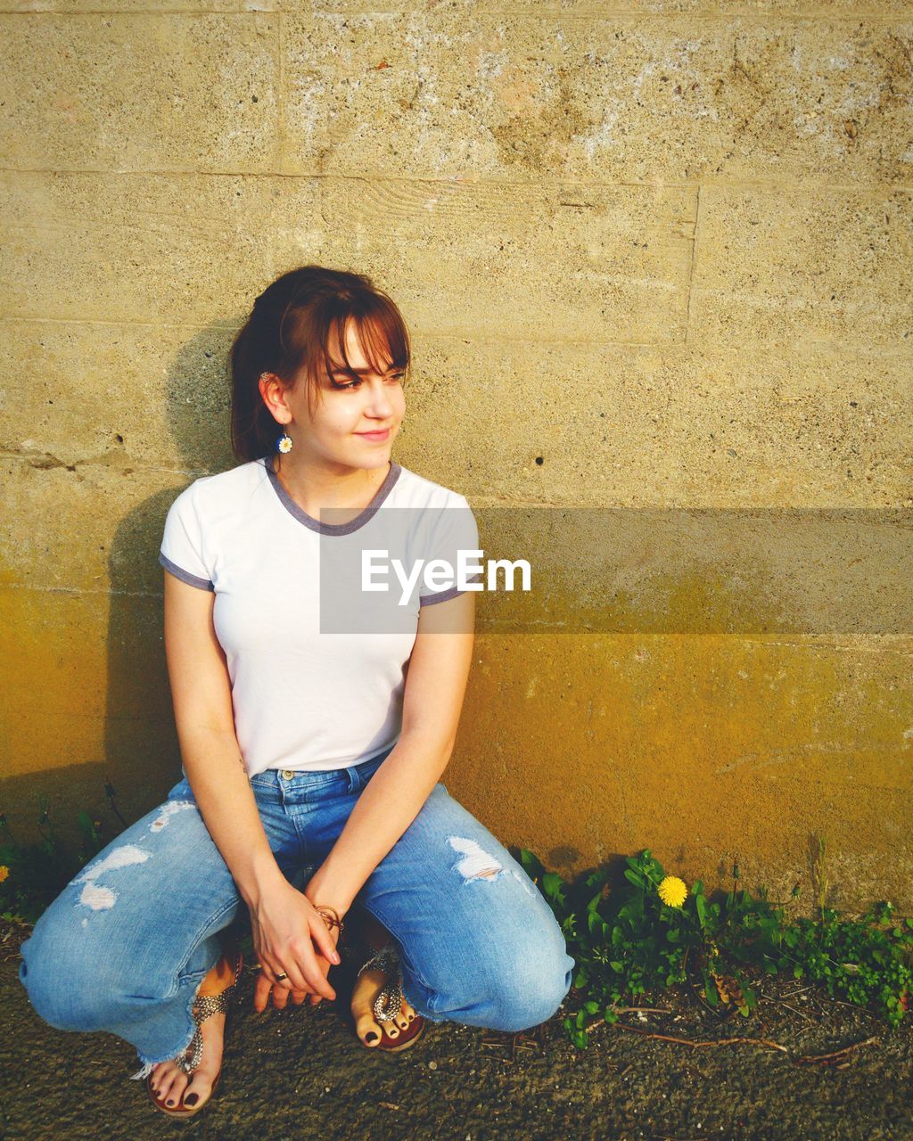 Thoughtful woman crouching against wall