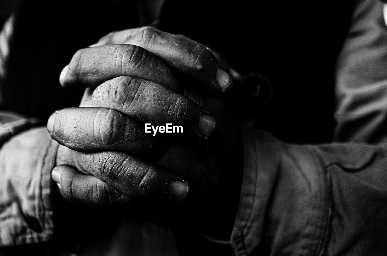 Midsection of man with hands clasped