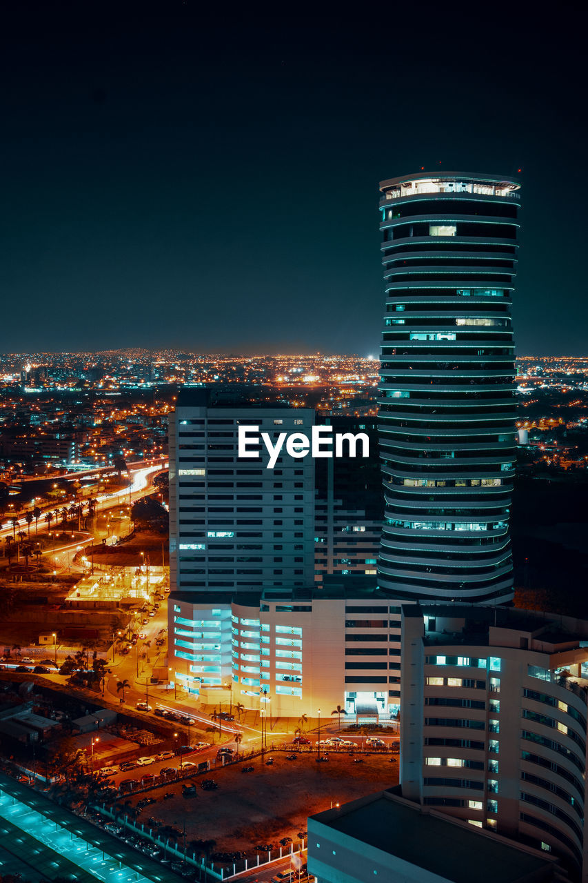 Illuminated buildings in city against sky at night