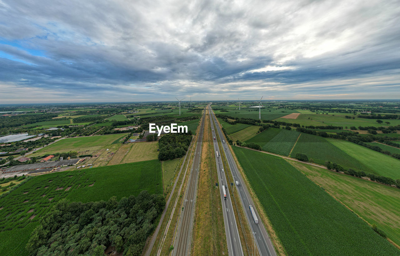 Panoramic view of wind farm or wind park,  with the motorway with few cars and railroad next to it.