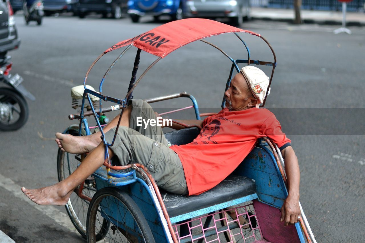 REAR VIEW OF BOY SITTING ON ROAD