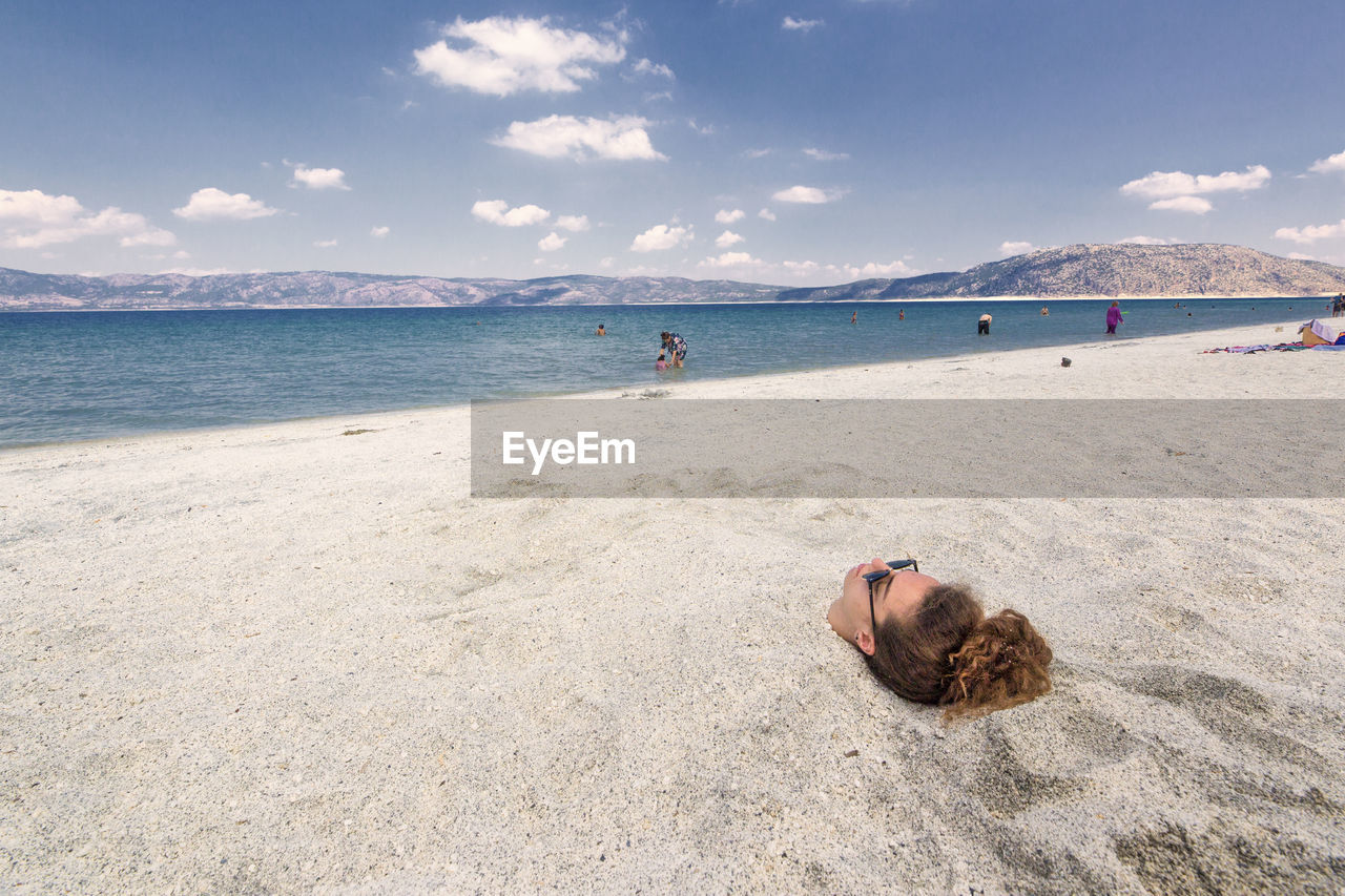 Young woman buried in sand at beach