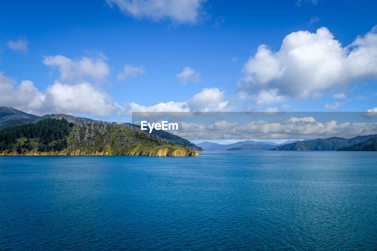 SCENIC VIEW OF SEA AND MOUNTAINS AGAINST BLUE SKY