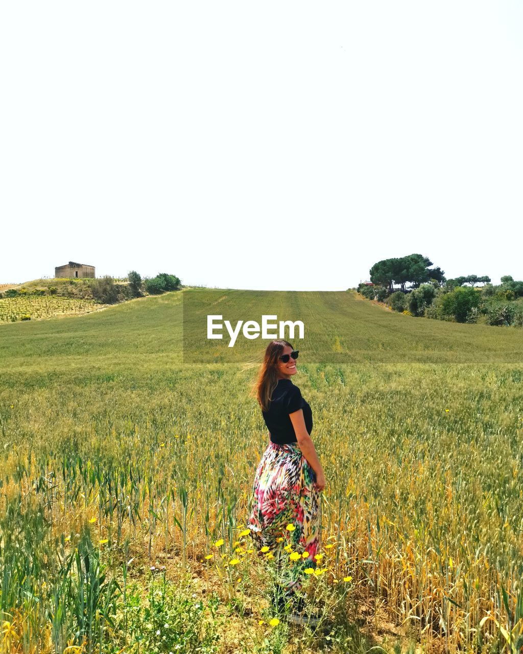 Portrait of woman standing on grassy land against clear sky