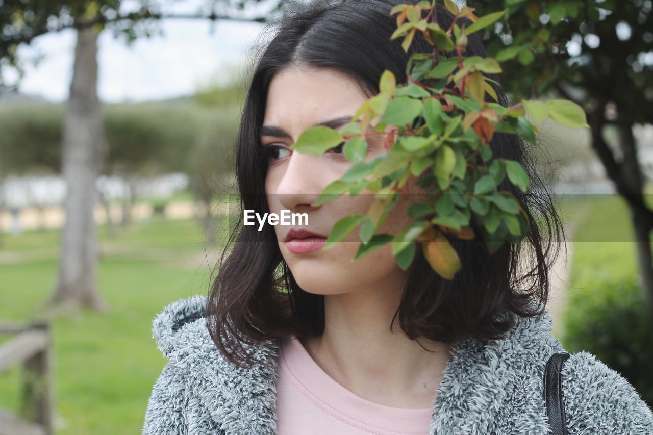 Close-up of young woman looking away at park