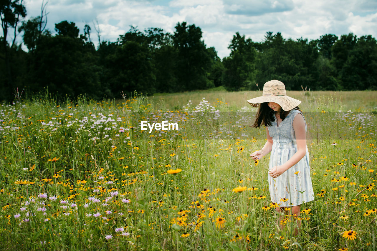Girl wearing a floppy sun hat picking flowers in southern michigan