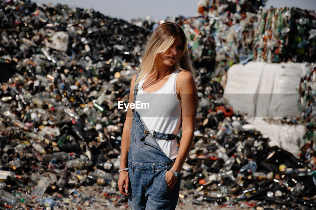 Young woman standing against garbage