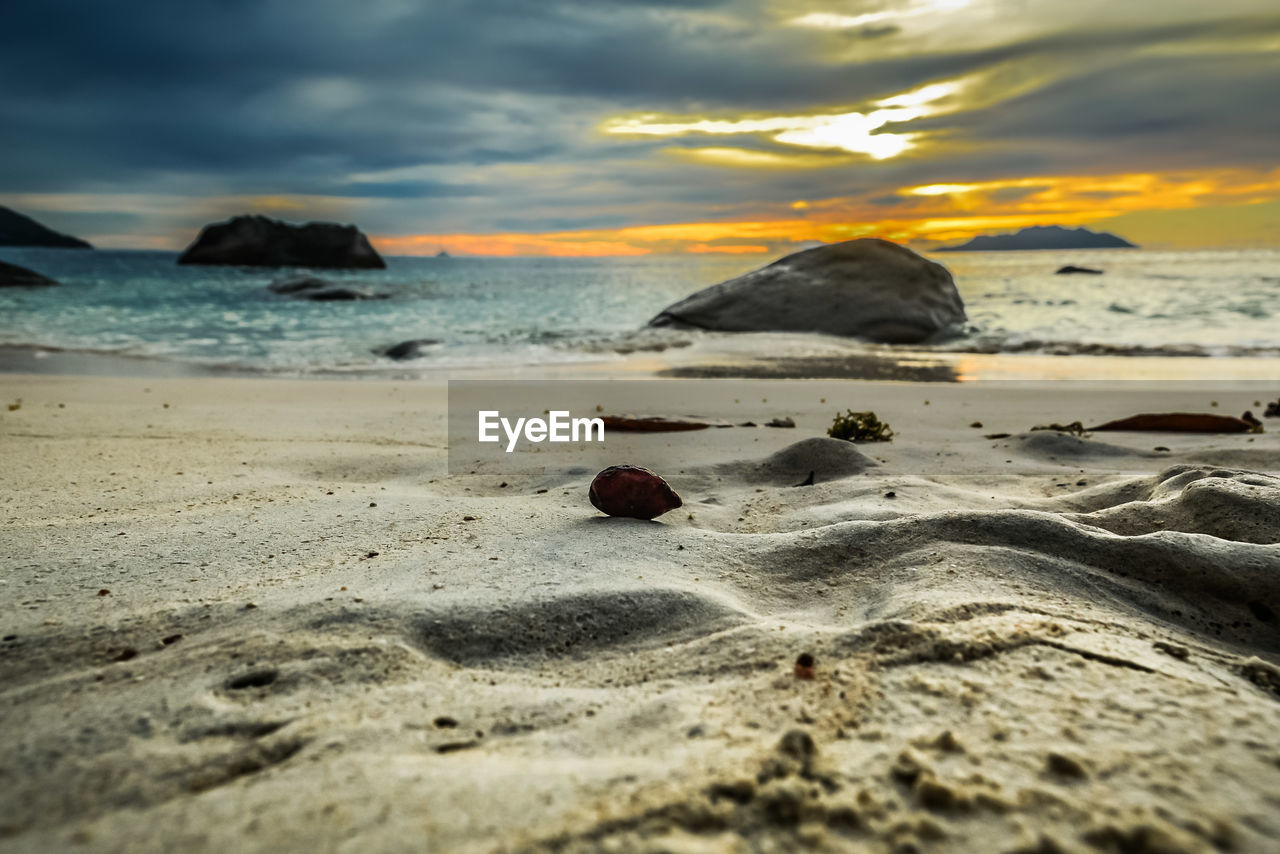 SURFACE LEVEL OF BEACH AGAINST SKY DURING SUNSET