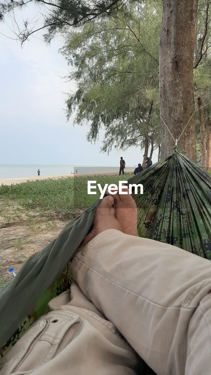 Low section of man lying in hammock