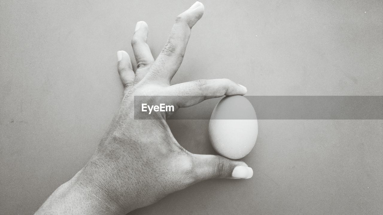 Cropped image of hand holding egg at table