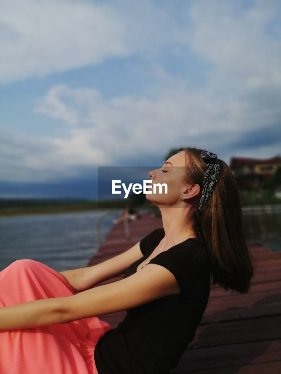 Side view of young woman standing against sky