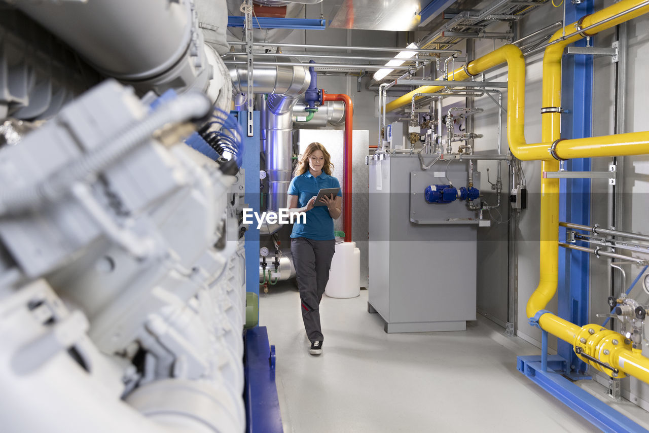 Technician using tablet pc walking in factory