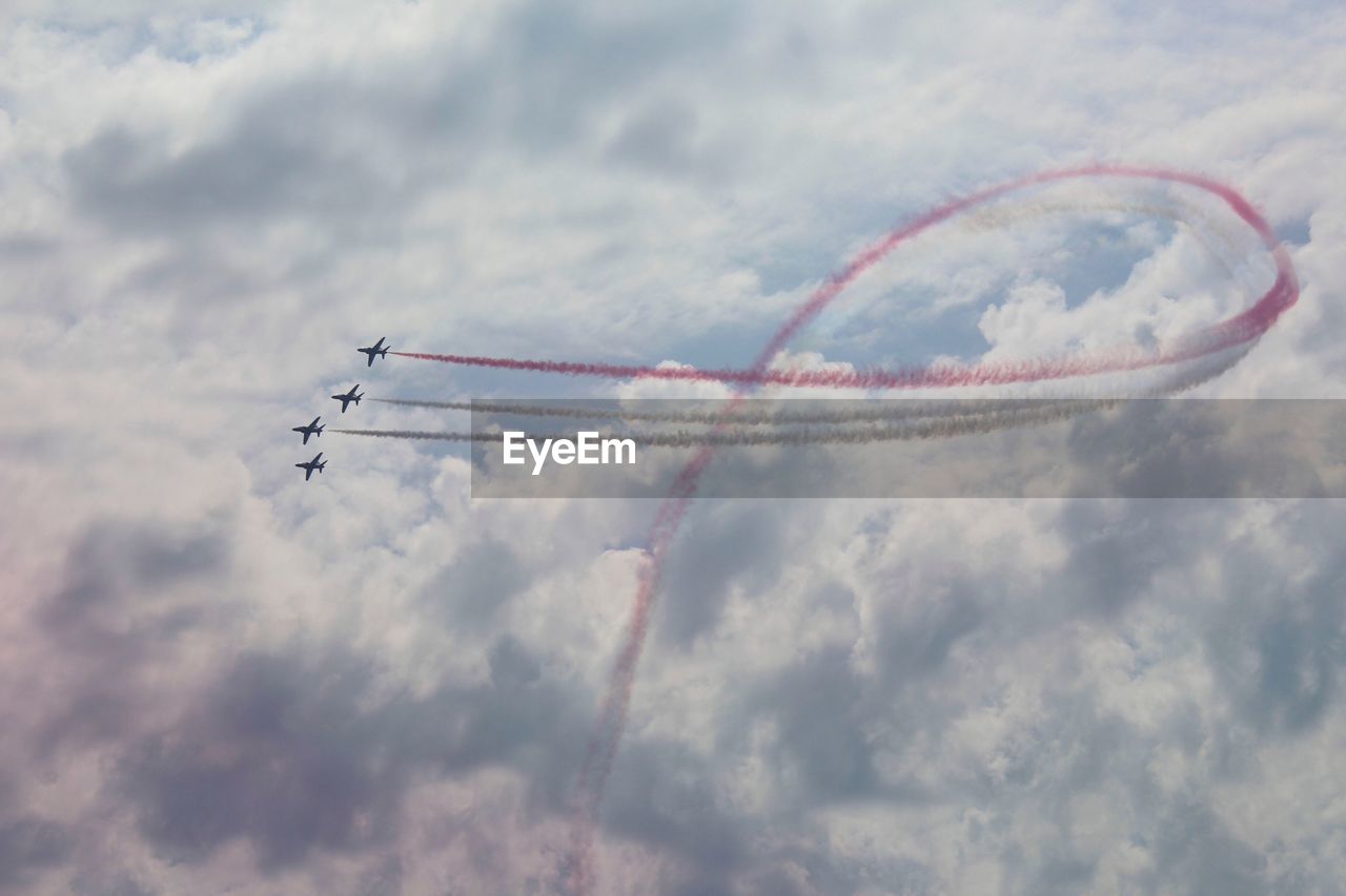 Low angle view of airshow against cloudy sky