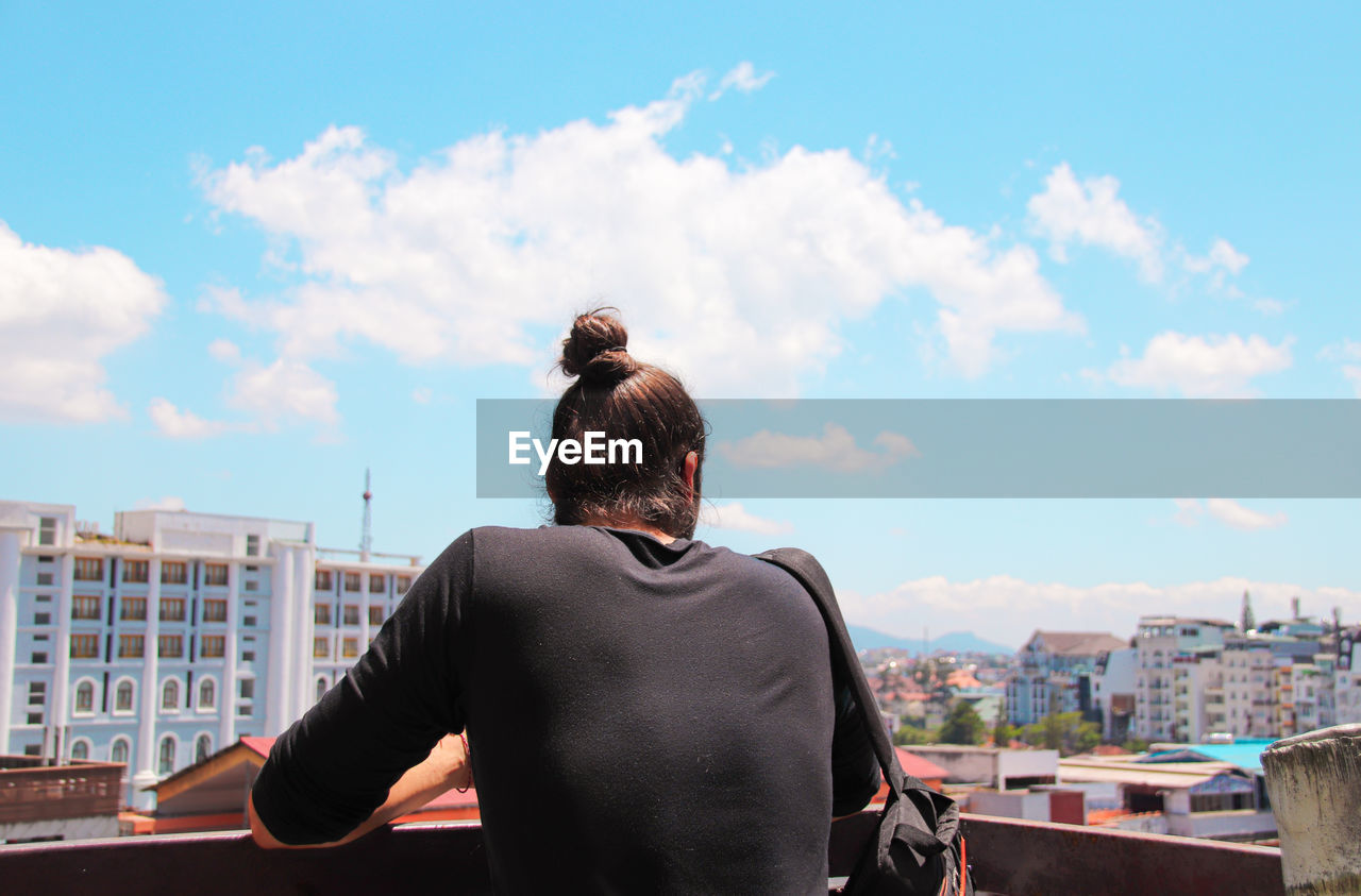 Rear view of man standing against buildings in city