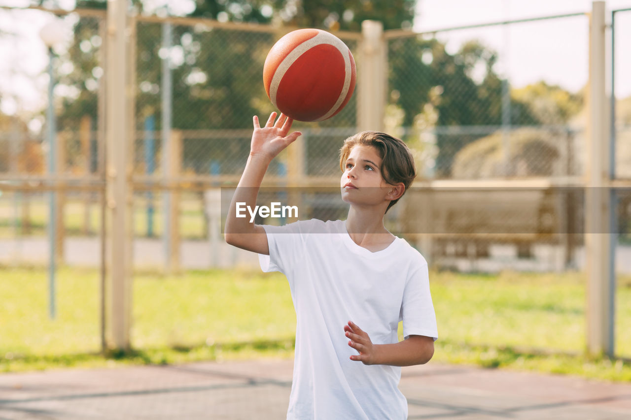 Boy playing with basketball in court