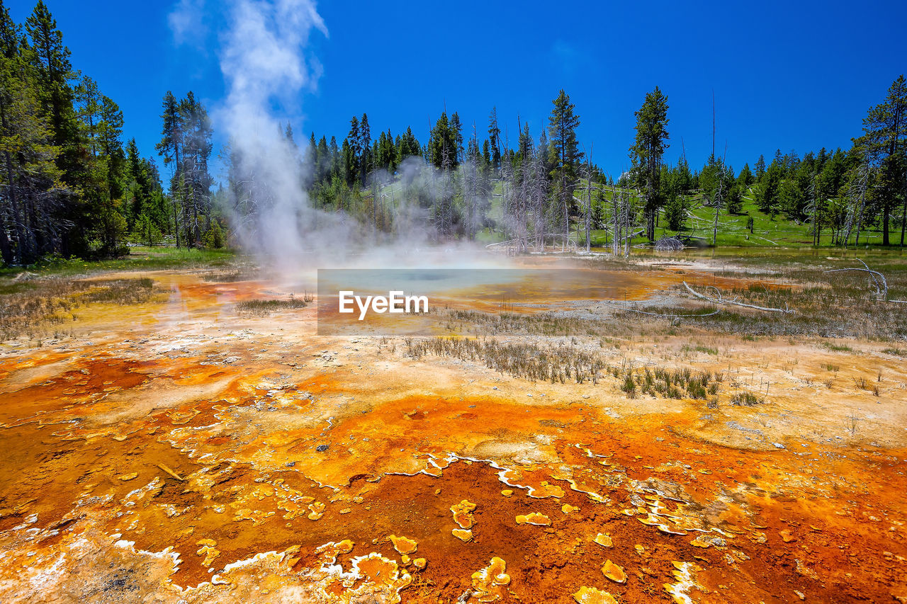 geology, steam, heat, landscape, beauty in nature, environment, wilderness, power in nature, hot spring, nature, scenics - nature, geyser, physical geography, sky, water, smoke, body of water, tree, non-urban scene, land, travel destinations, mountain, travel, no people, plant, leaf, blue, forest, volcano, tourism, day, volcanic landscape, outdoors, spring, cloud, autumn, accidents and disasters, natural phenomenon, national park, erupting, fire, extreme terrain, burning