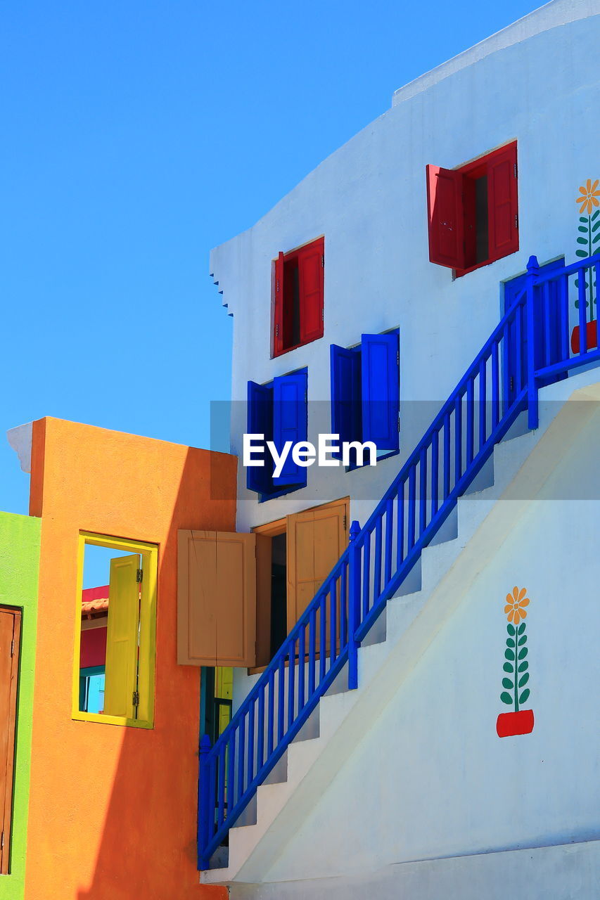 Low angle view of multi colored buildings against clear blue sky