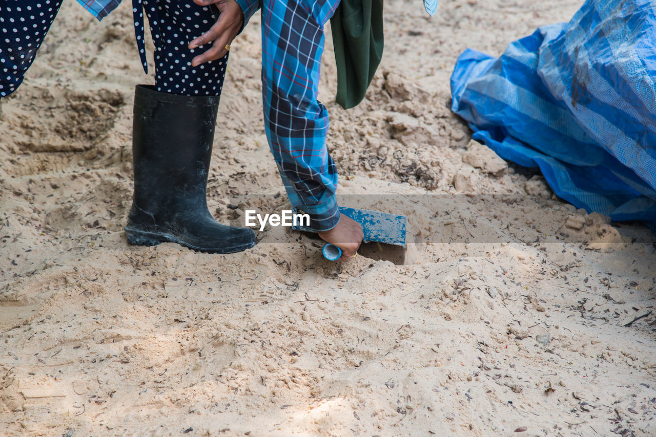 Low section of person cleaning sand at beach