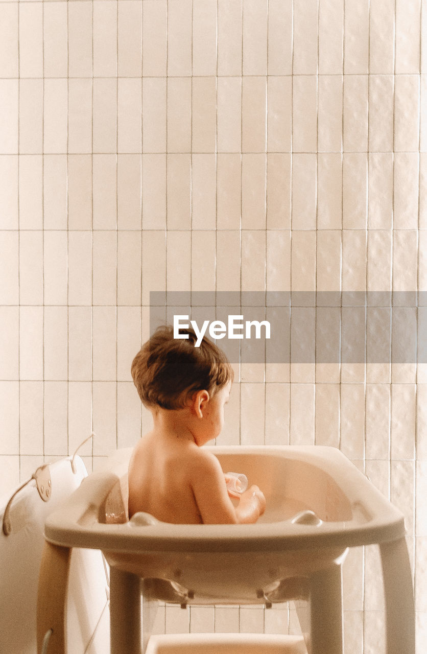 Portrait  of baby sitting in shower 