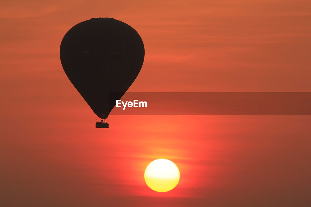 Silhouette hot air balloon against orange sky