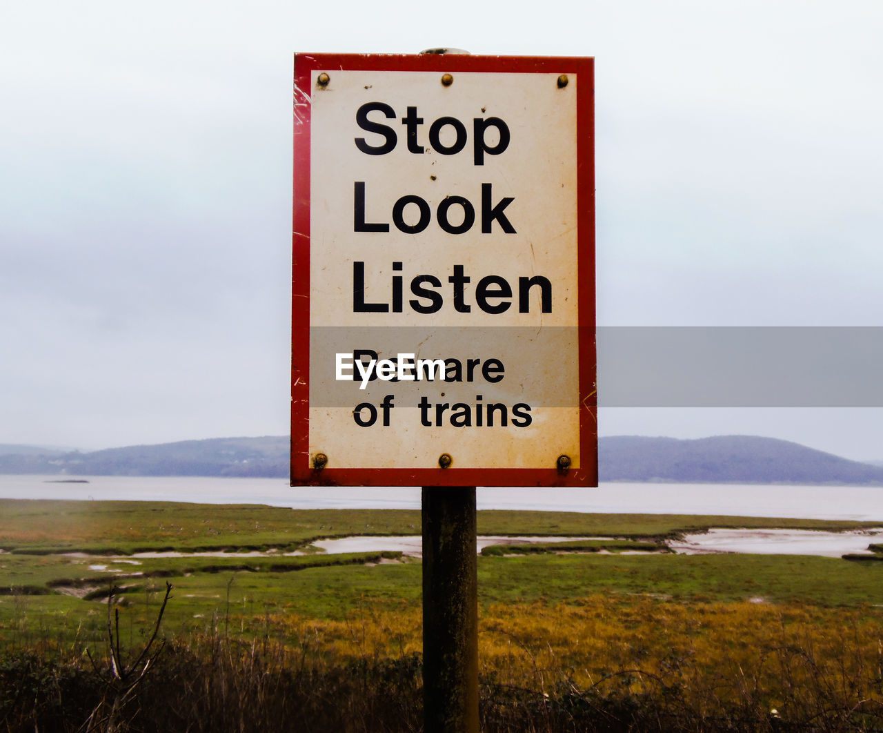 Close-up of warning sign on landscape against sky