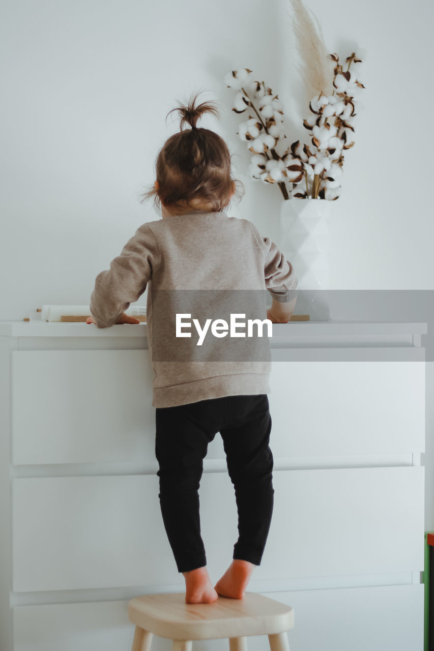 A child small girl stands backwards near white commode